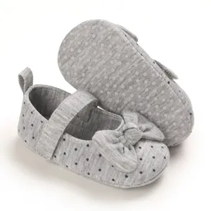 Detail view of grey polka dot baby girl soft sole walker shoes with bow decoration.