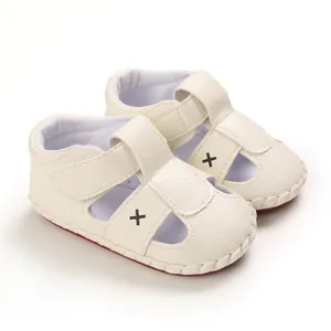 Detailed close-up of cream soft-sole baby pre-walker sandals with cross embroidery