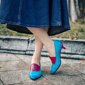 Detailaufnahme von retro blau-roten Lederschuhen mit Blumenprägung und Kitten-Heel