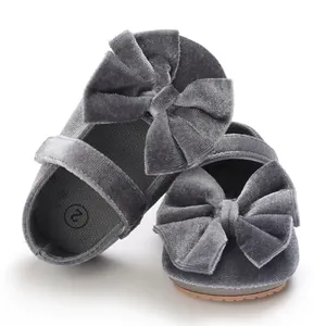 Close-up of grey velvet baby walker shoes with large decorative bows and anti-slip sole.