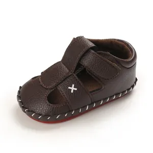 Close-up detail of brown baby soft sole sandals with cross embroidery