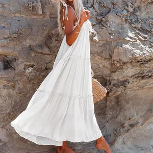 Full side view of a white tiered maxi sundress with thin straps in a rocky beach setting