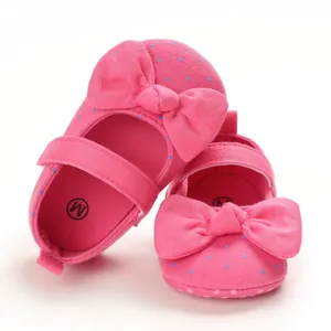 Macro view of soft-soled pink baby girl shoes with decorative bows and blue polka dots