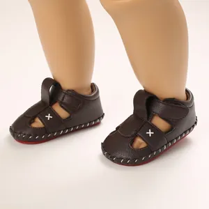 Detailed close-up of dark brown baby sandals with soft soles and red non-slip bottom.