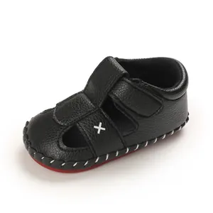 Detail of black baby walking sandal with soft non-slip sole and white cross accent.