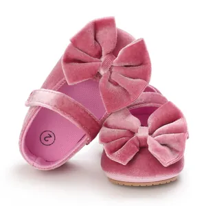 Close-up of pink velvet baby girl Mary Jane shoes with large decorative bows
