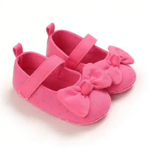 Pink polka dot baby girl shoes with decorative bow and soft fabric texture detail view