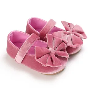 Detailed macro view of pink velvet baby girls' walking shoes featuring a large decorative bow