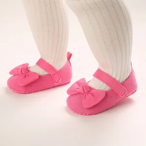 Macro detail of soft sole pink polka dot baby walker shoes for girls with large bow accent