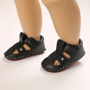 Detailed view of black faux leather baby sandals with soft non-slip red soles