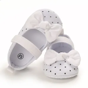 Detail view of baby girl white soft sole shoes with black polka dots and big bows