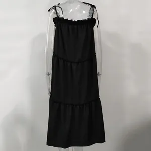 Detailed view of a solid black tiered strappy dress featuring adjustable shoulder ties.