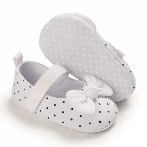 Close-up of white polka dot baby girl shoes with soft non-slip sole and bow