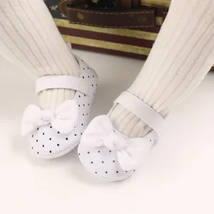 Close-up of white baby girl walking shoes with black polka dots and white bow detail