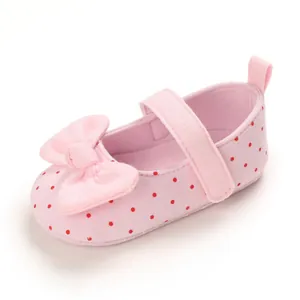 Close-up of pink baby girl princess shoe with red polka dots and bow detail.