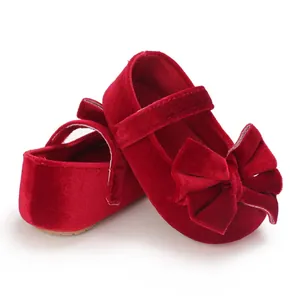 Detailed side view of red velvet baby shoes featuring a large elegant bow ornament
