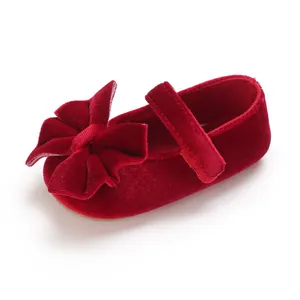 Close-up of elegant red velvet baby girl walking shoe featuring a large decorative bow