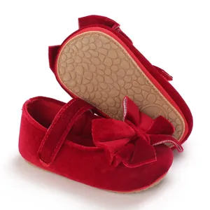 Detail of red velvet baby shoe showing large bow decoration and anti-slip rubber outsole