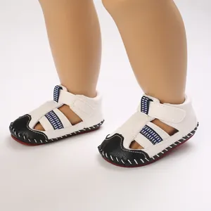 Vista detallada de sandalias blancas y negras para bebés con suelas de goma suave