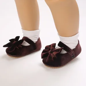 Close-up detail of burgundy velvet baby princess shoes with a large decorative bow