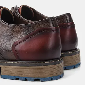 Close-up detail of men's burnished leather business shoes with blue non-slip sole