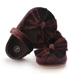 Macro view of dark burgundy velvet baby girl walker shoes featuring decorative large bows