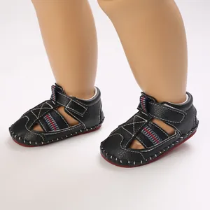 Primer plano de sandalias negras para bebé con suelas de goma blanda infantiles