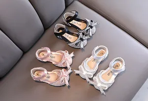 Dettaglio di scarpe da principessa per bambine con strass, perle e fiocchi in tre colori.