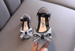 Dettaglio del fiocco con perle e strass sulle scarpe da principessa nere