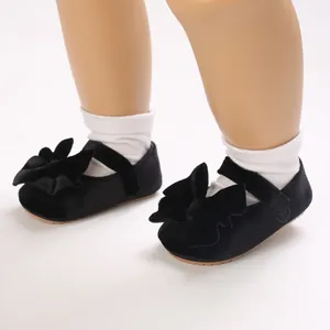 Close-up of black velvet baby princess shoes with a large decorative bow