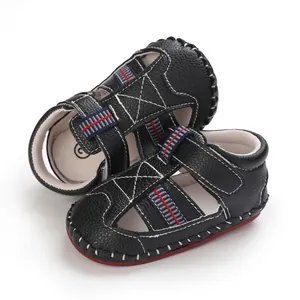 Primer plano de sandalias negras para bebés con rayas rojas y azules y suela blanda