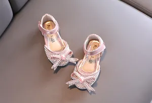 Dettaglio macro delle scarpe da principessa rosa per bambine con strass e fiocco di perle