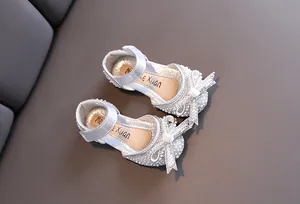 Vista dettagliata di scarpe da principessa argento con perle e fiocco di strass