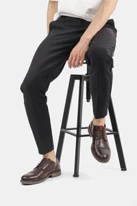 Detail of men's brown burnished leather oxfords styled with professional black trousers