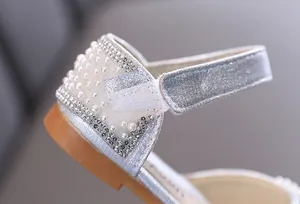 Dettaglio scarpa da ballo argento per bambina con eleganti perle e strass sul tacco.