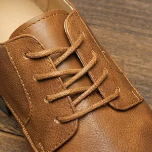 Close-up of brown leather men's formal shoes showing the textured lace-up detail