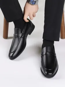 Close-up of stylish black leather loafers with stitching details on model's feet