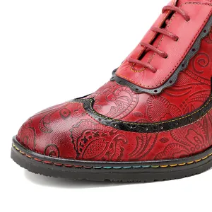 Gros plan sur une chaussure en cuir rouge avec motifs floraux gaufrés et coutures arc-en-ciel