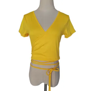 Dettaglio del crop top giallo con scollo a V e lacci regolabili in vita da annodare.