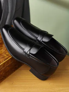 Macro view of polished black leather men's penny loafers with intricate U-tip stitching