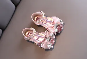 Vista detallada de zapatos de princesa rosa con un lazo grande y correa de perlas