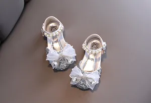 Primer plano de zapatos de princesa con purpurina plateada para niñas con perlas y lazo.