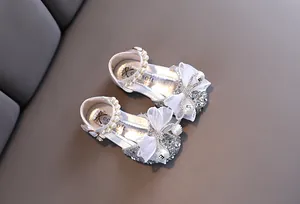Primer plano de zapatos de princesa plateados para niñas con elegantes lazos de perlas