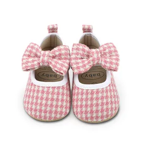 Close-up view of pink houndstooth baby girl pre-walker shoes featuring a large bow