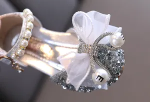 Primer plano de zapatos de princesa con purpurina plateada para niña y lazo blanco