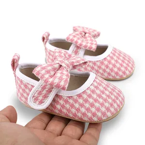 Detail of pink houndstooth baby girl shoes showing soft fabric texture and infant size