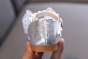 Primer plano de zapatos de princesa plateados brillantes con perlas y lazo elegante