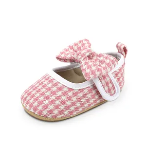 Detail view of pink houndstooth baby girl walking shoe with a decorative bow.