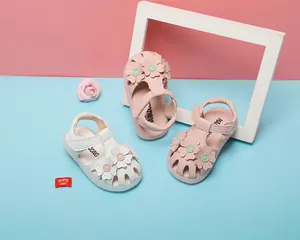 Nahaufnahme von süßen Baby-Mädchen-Sandalen mit Blumen in Rosa und Weiß mit weicher Sohle.