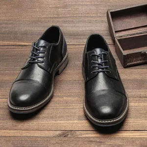 Detail of men's black cap-toe leather dress shoes on a vintage wood background
